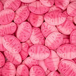 Close-up of pink oval candies with 'Milk' text on a pink background
