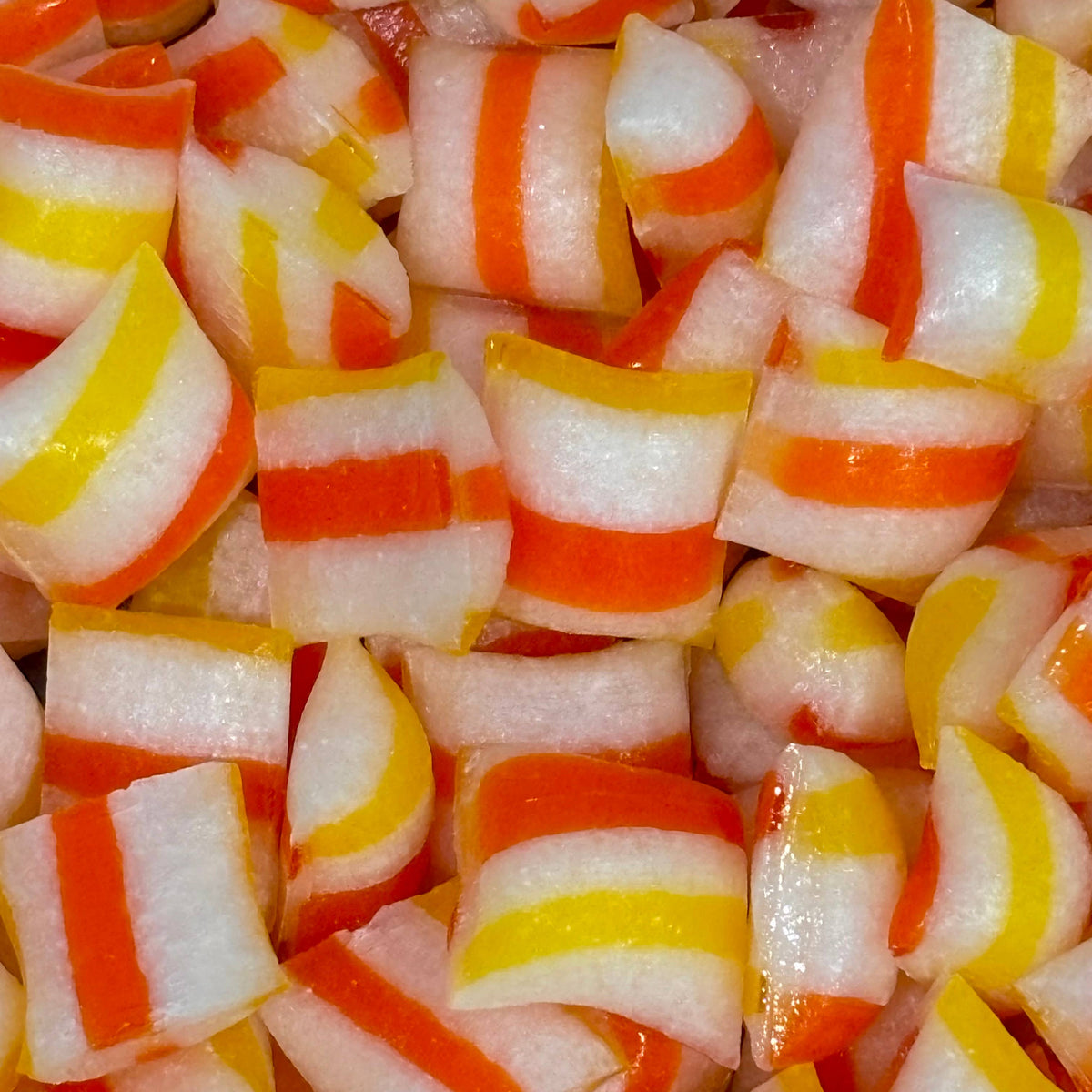Close-up of candy corn with red, yellow, and white stripes.